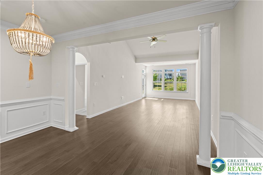 4758 Rafi Road Easton, PA 18045 - Photo 17 of 55 An elegant chandelier illuminates the dining area, flowing seamlessly into a well-lit living space with ample windows.