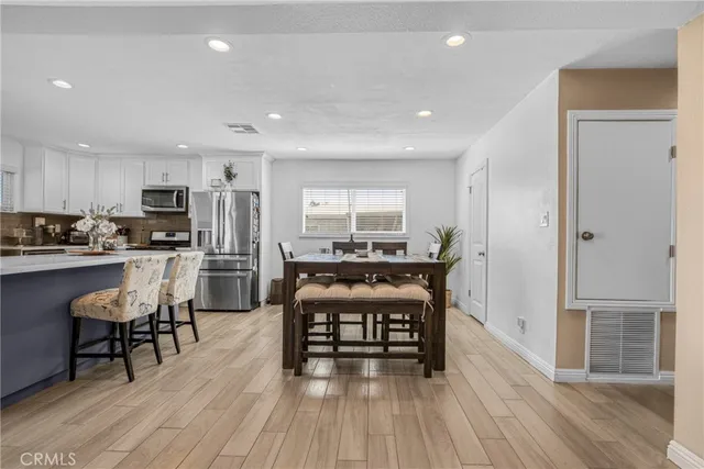 a kitchen with stainless steel appliances a dining table chairs stove and refrigerator