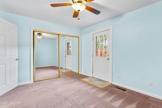 a view of an empty room with window and a ceiling fan