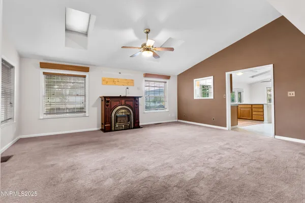 an empty room with windows fireplace and a chandelier fan