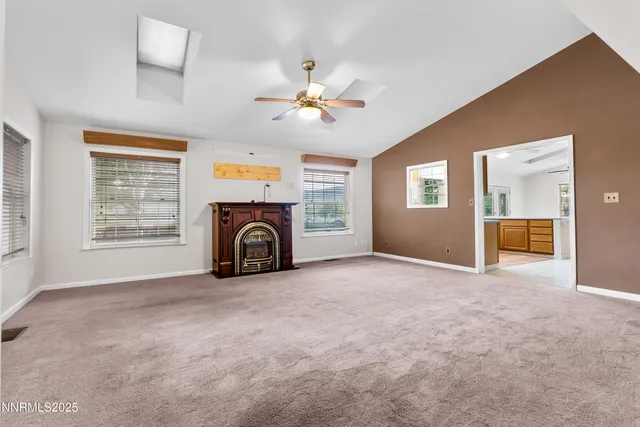 an empty room with windows fireplace and a chandelier fan