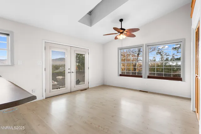 a view of an empty room with chandelier fan and wooden floor