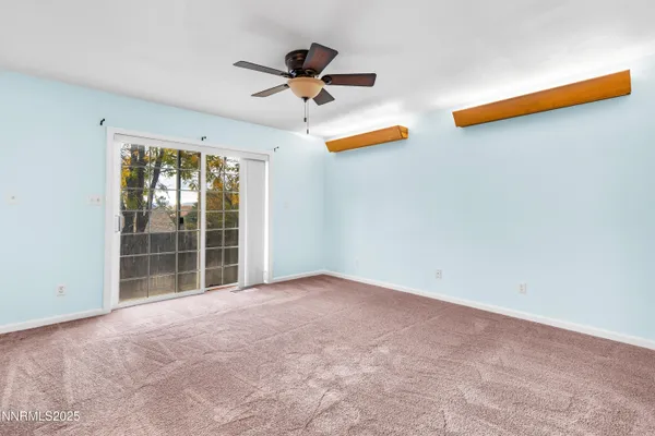 a view of an empty room with a ceiling fan and window