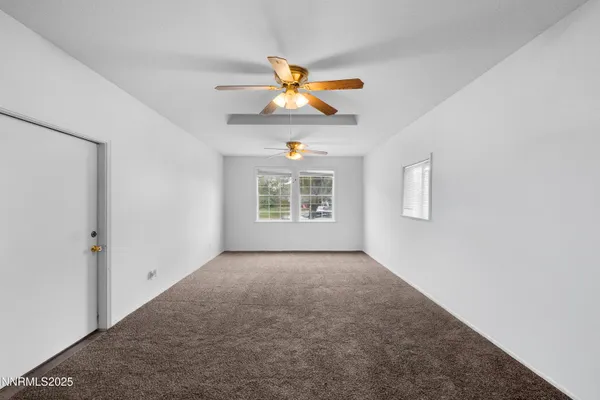 a view of an empty room with window and a ceiling fan
