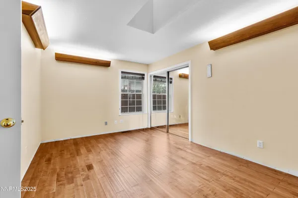 a view of empty room with wooden floor and fan