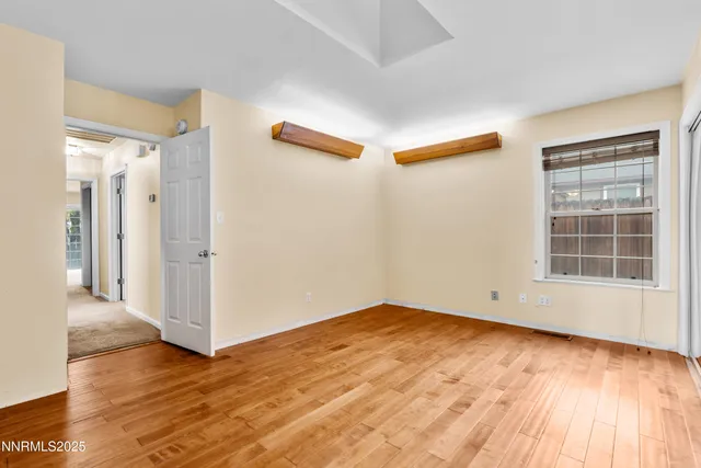a view of empty room with wooden floor and fan
