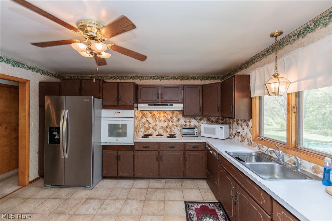 2170 Norton Road Stow, OH 44224 - Photo 34 of 48 Kitchen featuring wood-finish cabinetry, stainless steel refrigerator, built-in wall oven, tiled flooring, and a large window overlooking exterior greenery