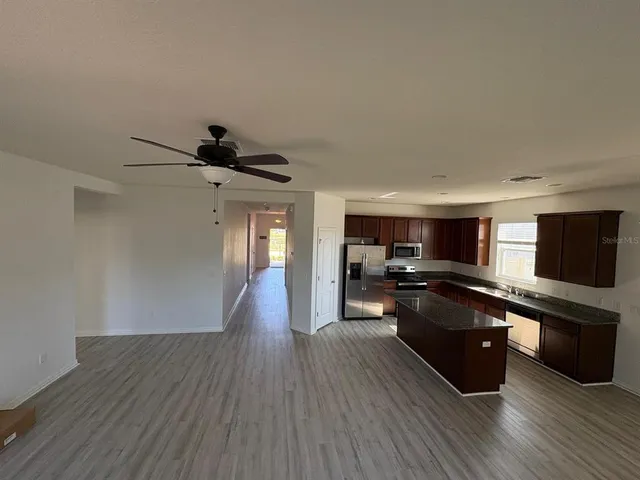 a living room with stainless steel appliances furniture and a flat screen tv
