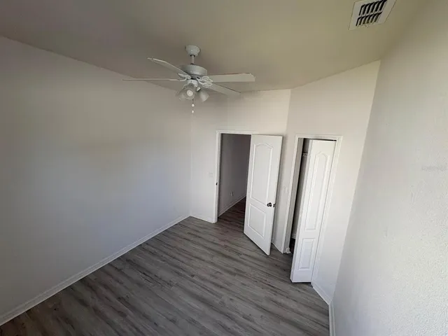 an empty room with wooden floor and ceiling fan