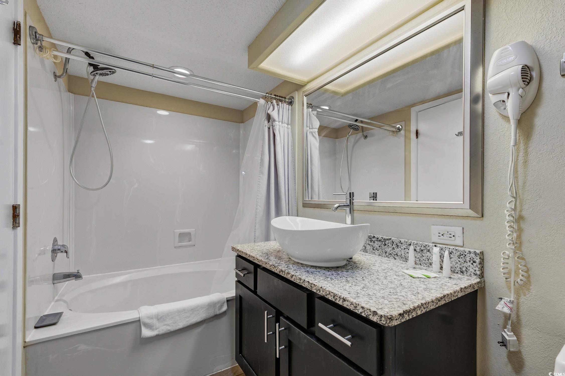 1702 North Ocean Boulevard, Unit 355 Myrtle Beach, SC 29577 - Photo 12 of 27 Full bathroom with shower / bath combo with shower curtain, vanity, and a textured wall
