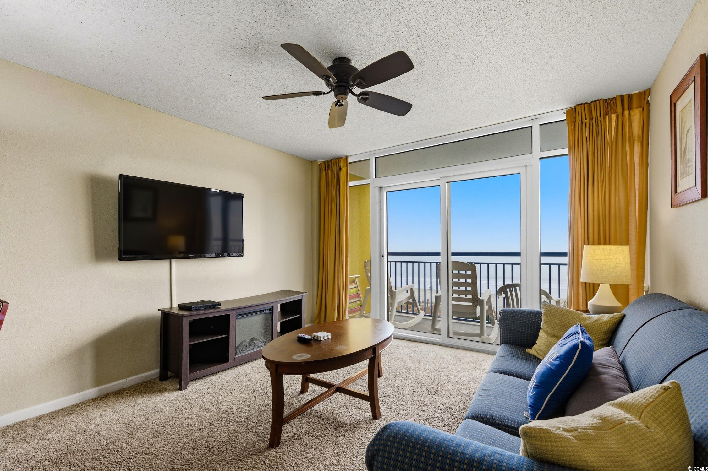 1702 North Ocean Boulevard, Unit 355 Myrtle Beach, SC 29577 - Photo 9 of 27 Carpeted living area featuring a textured ceiling, ceiling fan, and expansive windows