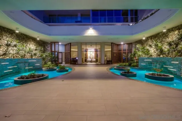 a palm tree sitting in front of a house with potted plants