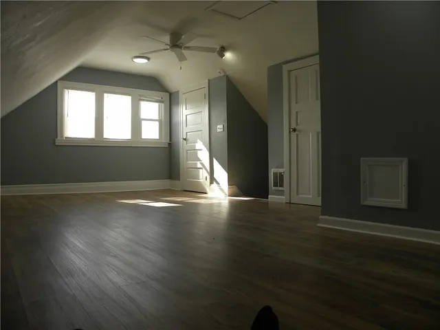 an empty room with wooden floor and windows with curtains