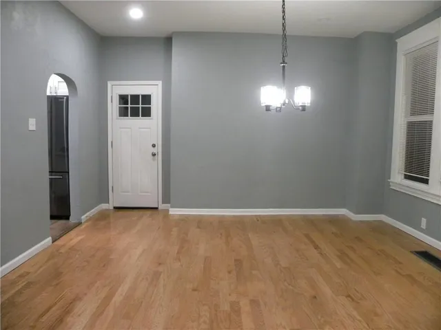 a view of an empty room with window and wooden floor
