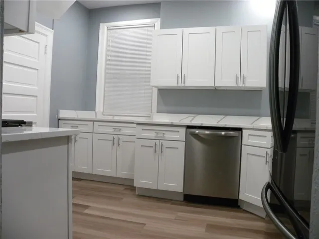 a kitchen with white cabinets and a refrigerator