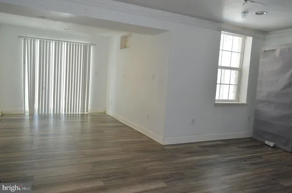 an empty room with wooden floor and windows with curtains