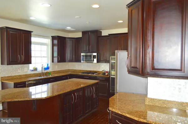 a kitchen with kitchen island granite countertop a sink stove and refrigerator