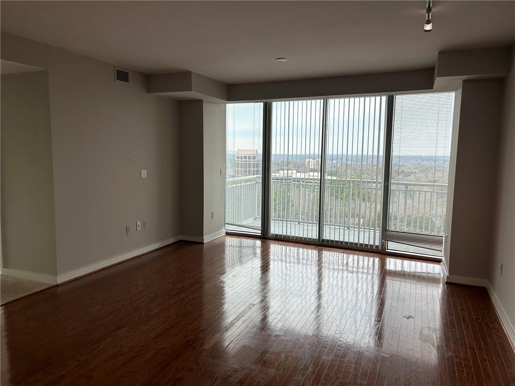 a view of an empty room with wooden floor and a window