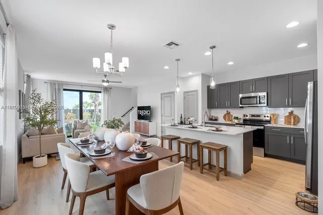a living room with stainless steel appliances kitchen island granite countertop furniture wooden floor and a chandelier