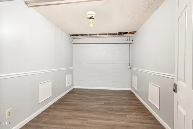 a view of a hallway with wooden floor and a bathroom