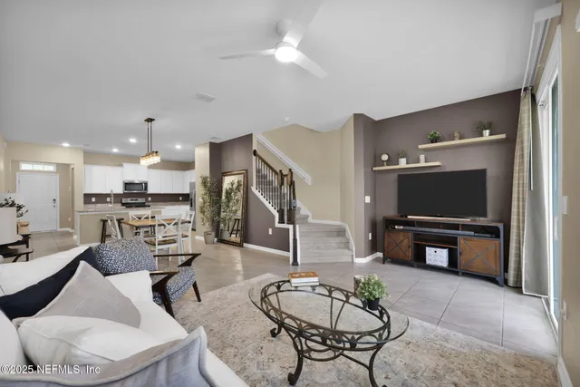 a living room with furniture a flat screen tv and kitchen view