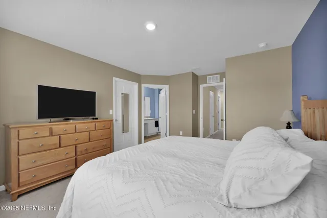 a bedroom with a bed and a flat screen tv in white walls