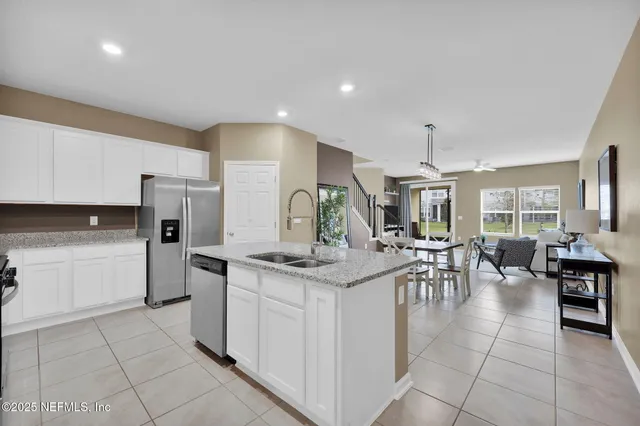 a kitchen with stainless steel appliances kitchen island granite countertop a table chairs and a refrigerator