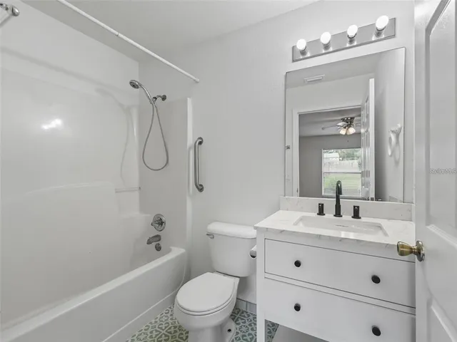 a bathroom with a sink vanity mirror bathtub and toilet