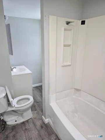 a white toilet sitting next to a bath tub