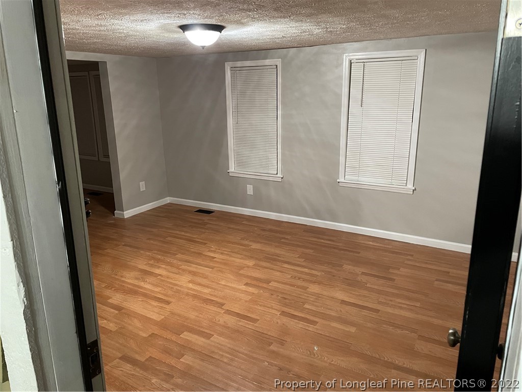 1215-1219 Camden Road Fayetteville, NC 28306 - Photo 23 of 25 an empty room with wooden floor and windows
