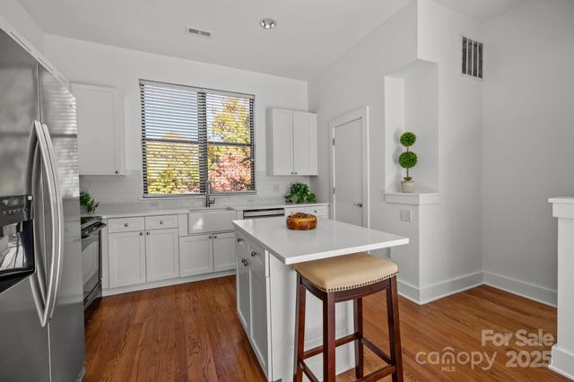 a kitchen with stainless steel appliances a stove a refrigerator and a dining table with wooden floor