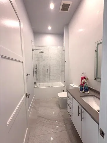a bathroom with a double vanity sink toilet mirror and shower
