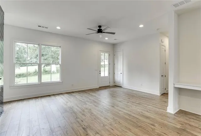 an empty room with wooden floor cabinet and windows