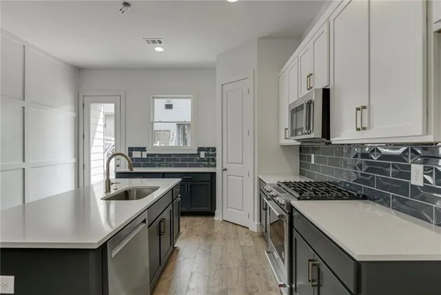 a kitchen with stainless steel appliances granite countertop a sink a stove and a refrigerator