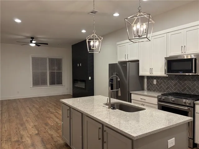 a kitchen with stainless steel appliances granite countertop a refrigerator a stove and a microwave