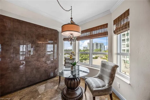 a dining room with furniture large windows and a chandelier