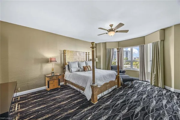 a bedroom with a large bed and a chandelier fan