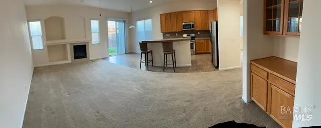 a kitchen with stainless steel appliances kitchen island granite countertop a refrigerator a stove top oven a sink and a refrigerator