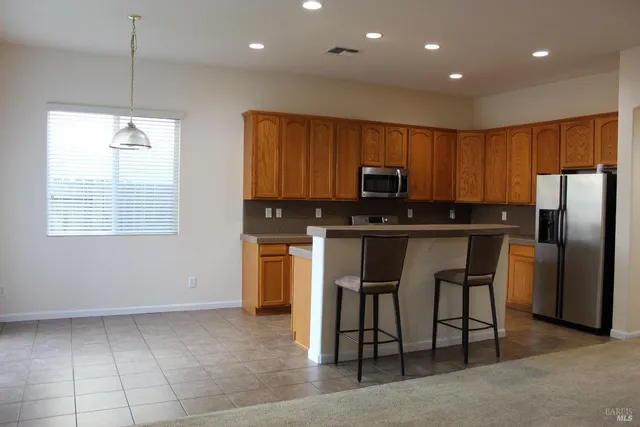 a kitchen with stainless steel appliances granite countertop a stove a sink a microwave a refrigerator and a cabinets