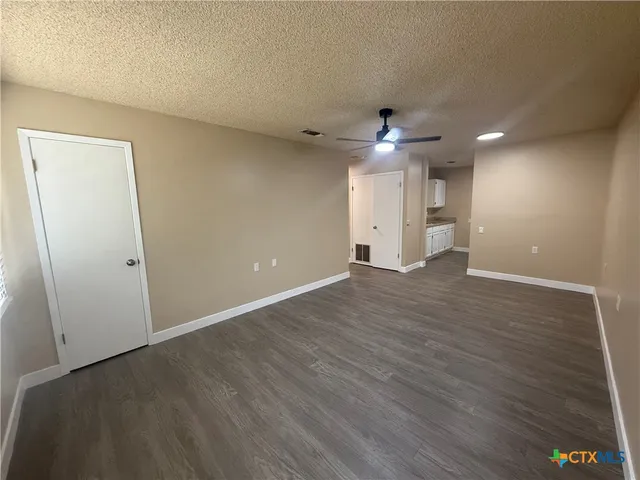 an empty room with wooden floor and a ceiling fan