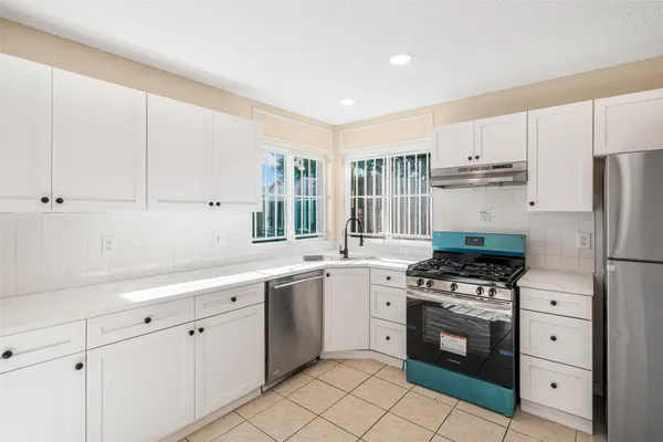 a kitchen with white cabinets sink and stainless steel appliances