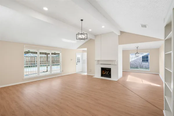 an empty room with windows fireplace and wooden floor