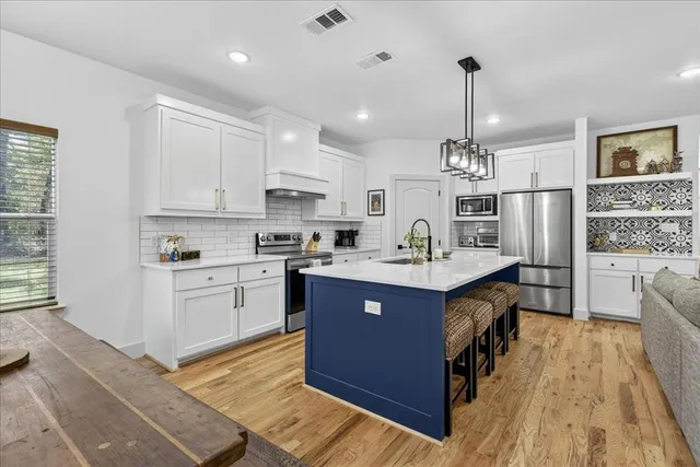 a kitchen with wooden cabinets a sink dishwasher a stove and a dining table with wooden floor