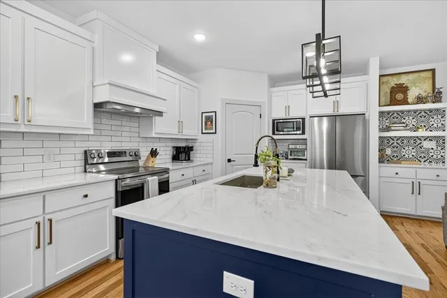 a kitchen with a refrigerator a stove a sink dishwasher and white cabinets with wooden floor