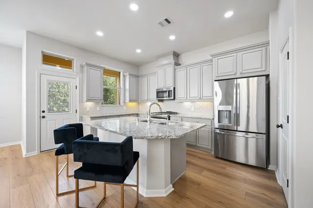 a kitchen with kitchen island granite countertop a sink cabinets and stainless steel appliances