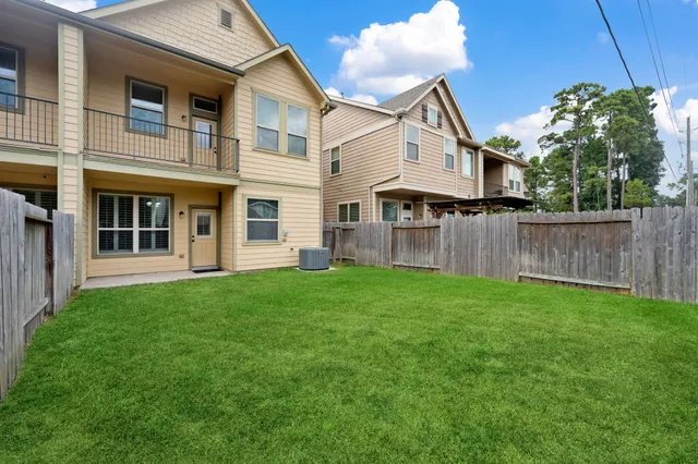 a view of a yard in front of a house with plants and wooden fence
