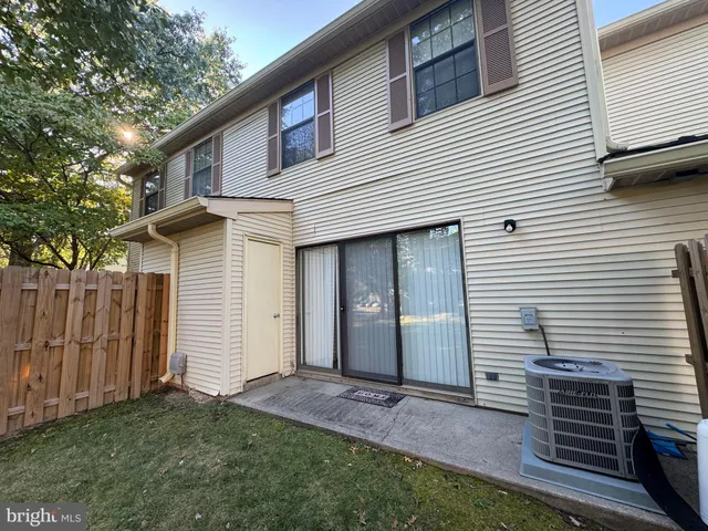 a view of backyard of small house with wooden fence