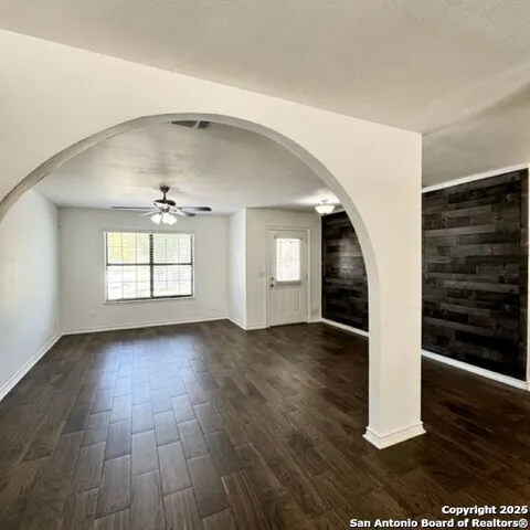 an empty room with wooden floor chandelier and windows