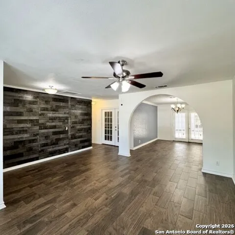 a view of an empty room with wooden floor and a ceiling fan