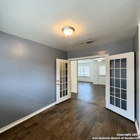 an empty room with wooden floor and windows